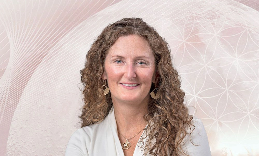 Headshot of Elisa Shine, a hypnosis and healing specialist in Nelson, BC, smiling in front of a soft pink geometric background.